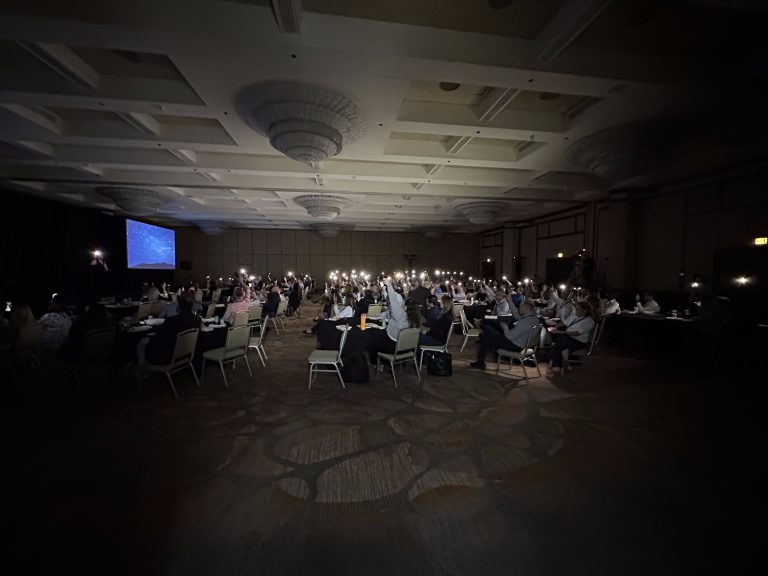 Audience in a darkened ballroom during an event presentation