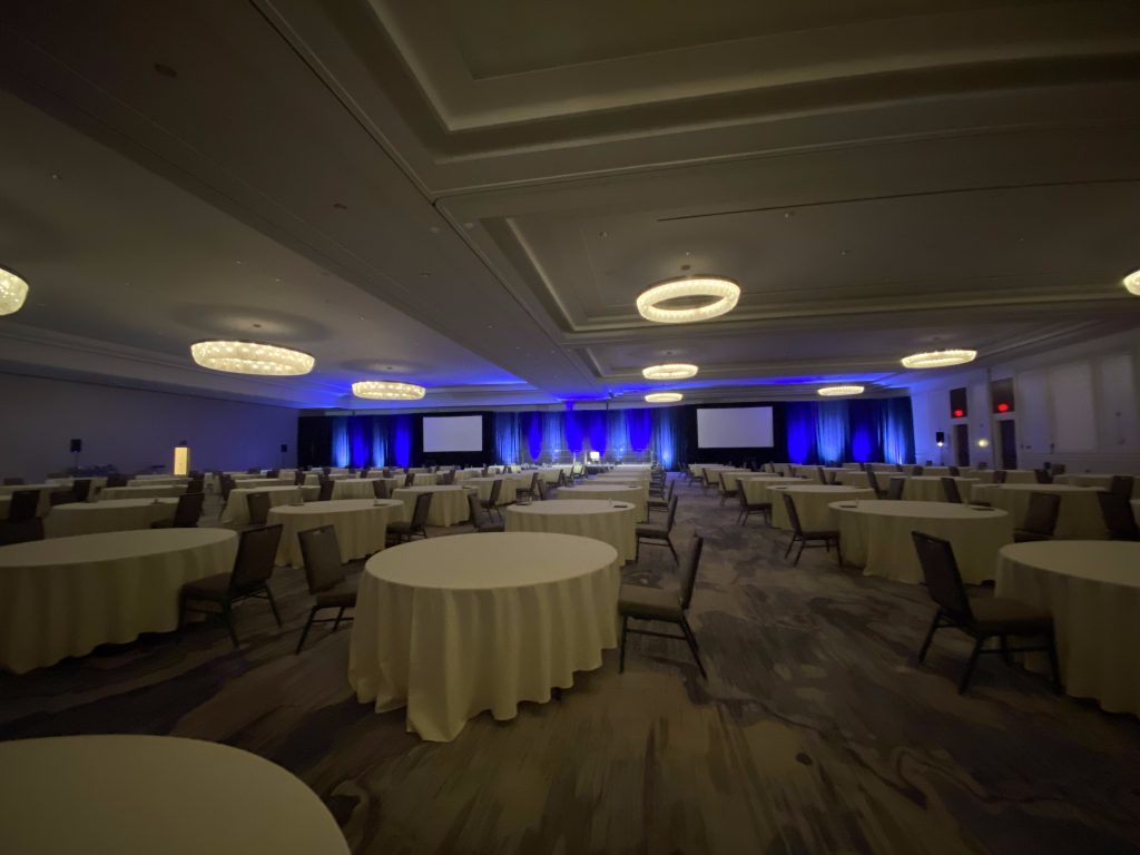Ballroom with round tables and stage screens set by CitiView Audio Visual