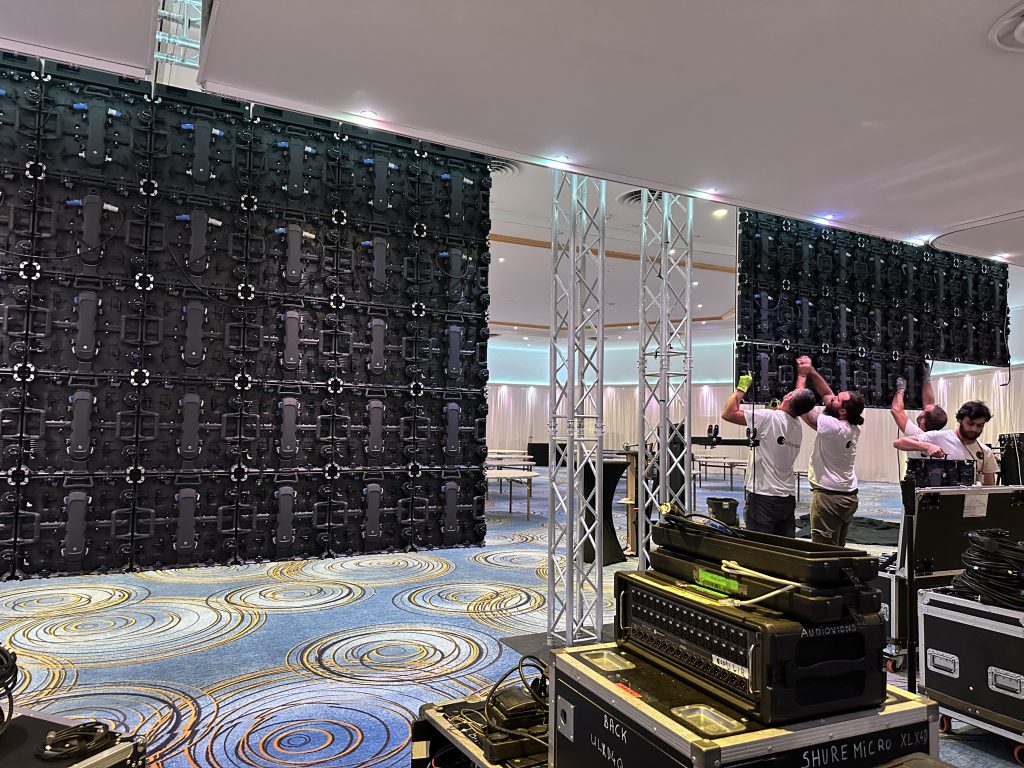 Crew assembling LED video wall panels on truss rigging for corporate event